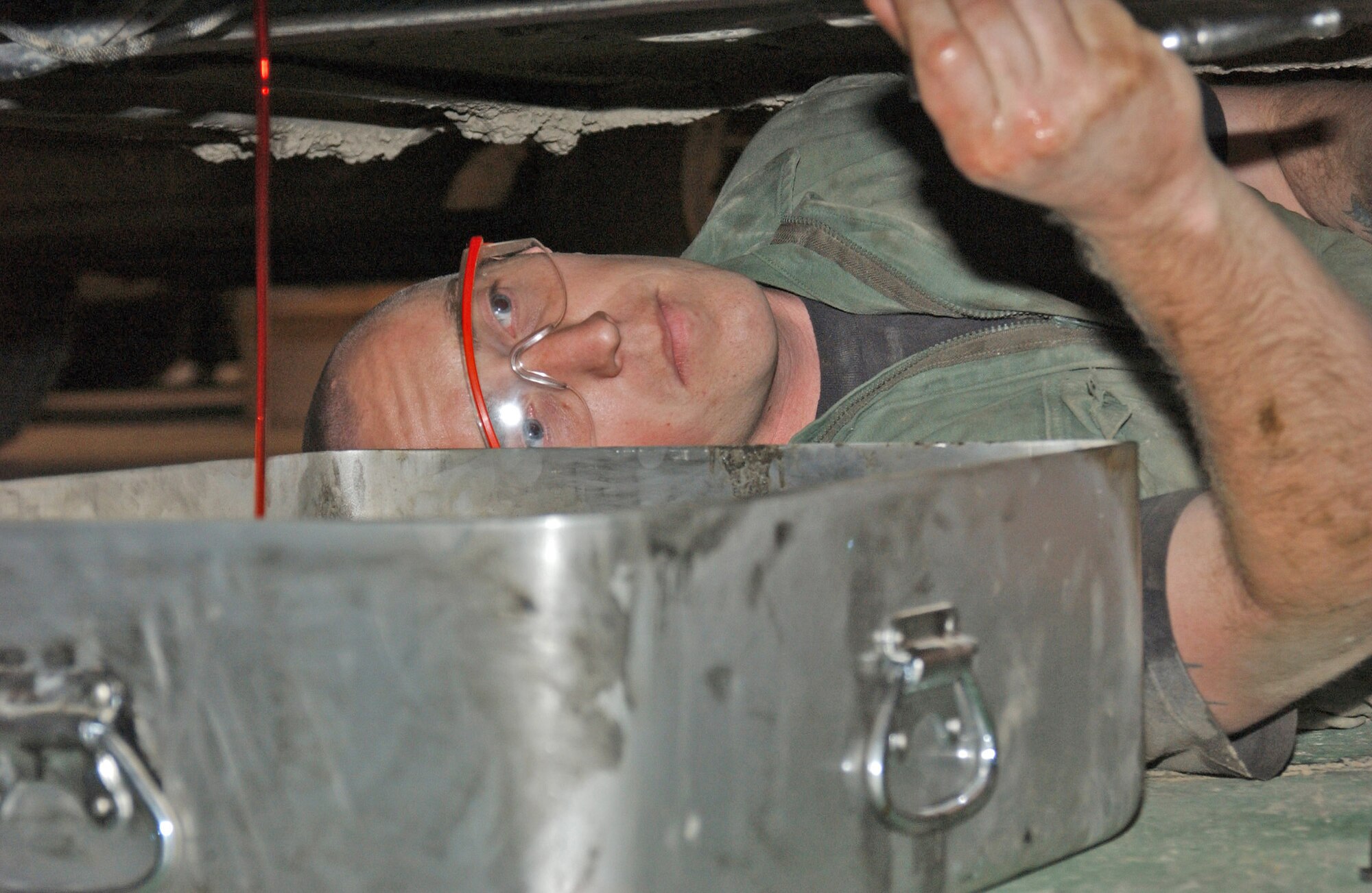 ALI BASE, Iraq (AFPN) -- Staff Sgt. Kevin Chandler checks a vehicle's underside while he drains fluid.  Vehicle maintenance is a 24/7 operation here. The maintainers assign the highest priority to security forces vehicles because of their security missions. Staff Sgt. Kevin Chandler is a vehicle maintenance journeyman with the 407th Expeditionary Logistics Readiness Squadron. (U.S. Air Force photo by Tech. Sgt. Paul Dean)
