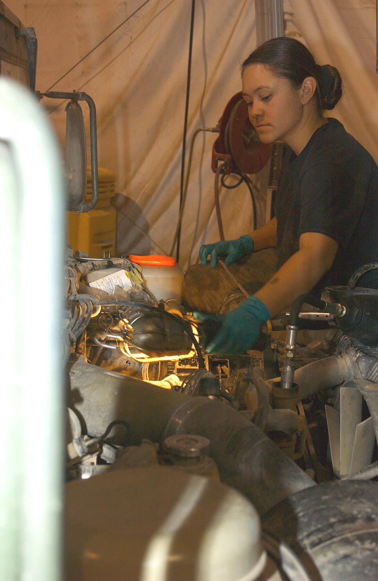 ALI BASE, Iraq (AFPN) -- Airman 1st Class Sara Gaines lights the area around a fuel filter she is replacing on a vehicle here.  Vehicle maintenance is a 24/7 operation here.  The maintainers assign the highest priority to security forces vehicles because of their security missions.  Airman Gaines is a vehicle maintenance journeyman with the 407th Expeditionary Logistics Readiness Squadron.   (U.S. Air Force photo by Tech. Sgt. Paul Dean)