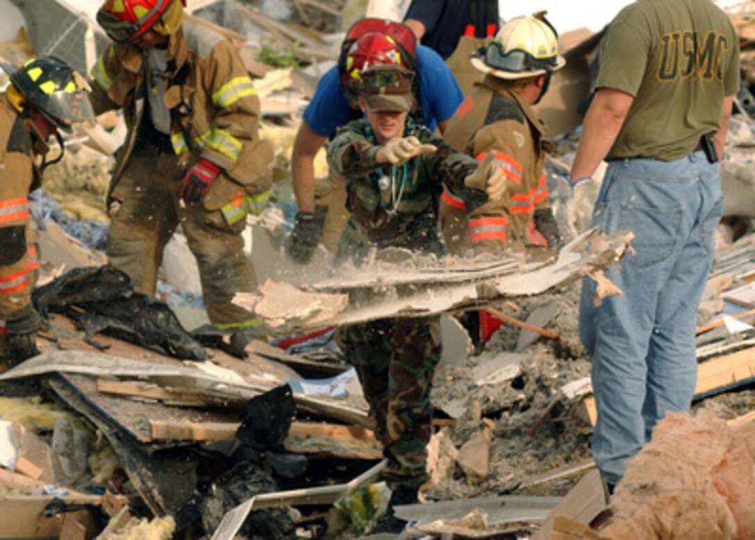 Navy Petty Officer 3rd Class Amy Gorman tosses aside some debris as she assists in search and rescue efforts in a tornado-damaged mobile home park in Evansville, Ind., on Nov. 6, 2005. Naval Reservists assigned to Navy Reserve Center Evansville are assisting local authorities in search and rescue efforts after an F3 tornado cut a 15-mile path through Eastern Indiana and Kentucky. Gorman, a hospital corpsman, is assigned to Navy Reserve Operational Hospital Support Unit Great Lakes, Detachment 23. 