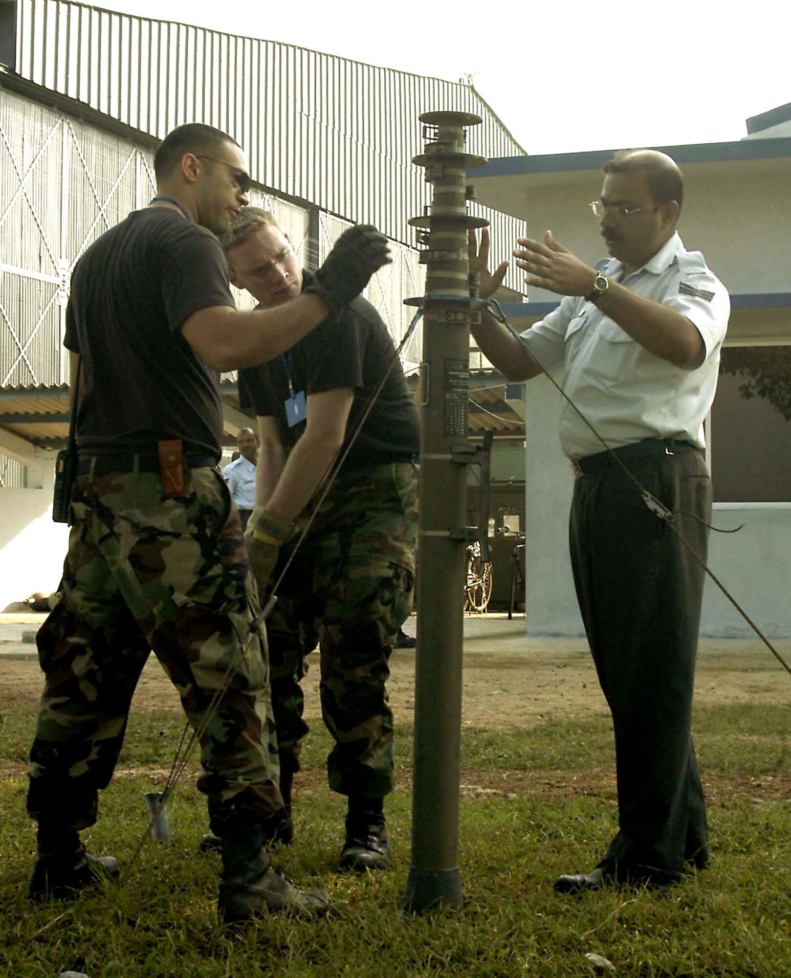 KALAIKUNDA AIR STATION, India -- Staff Sgt. Alan Pickford, Satellite Communications Specialist, tightens a guide wire on an antenna base as Staff Sgt. Eric Uptegrove, Airfield Maintenance Specialist, explains to Indian air force Sergeant Karmakar how to set up the antenna which will be used as the base station by the maintenance operations center. Both Sergeants Uptegrove and Pickford are deployed from the 35th Communications Squadron in support of exercise Cope India '06.  (U.S. Air Force photo by Tech. Sgt. Martin Jackson)