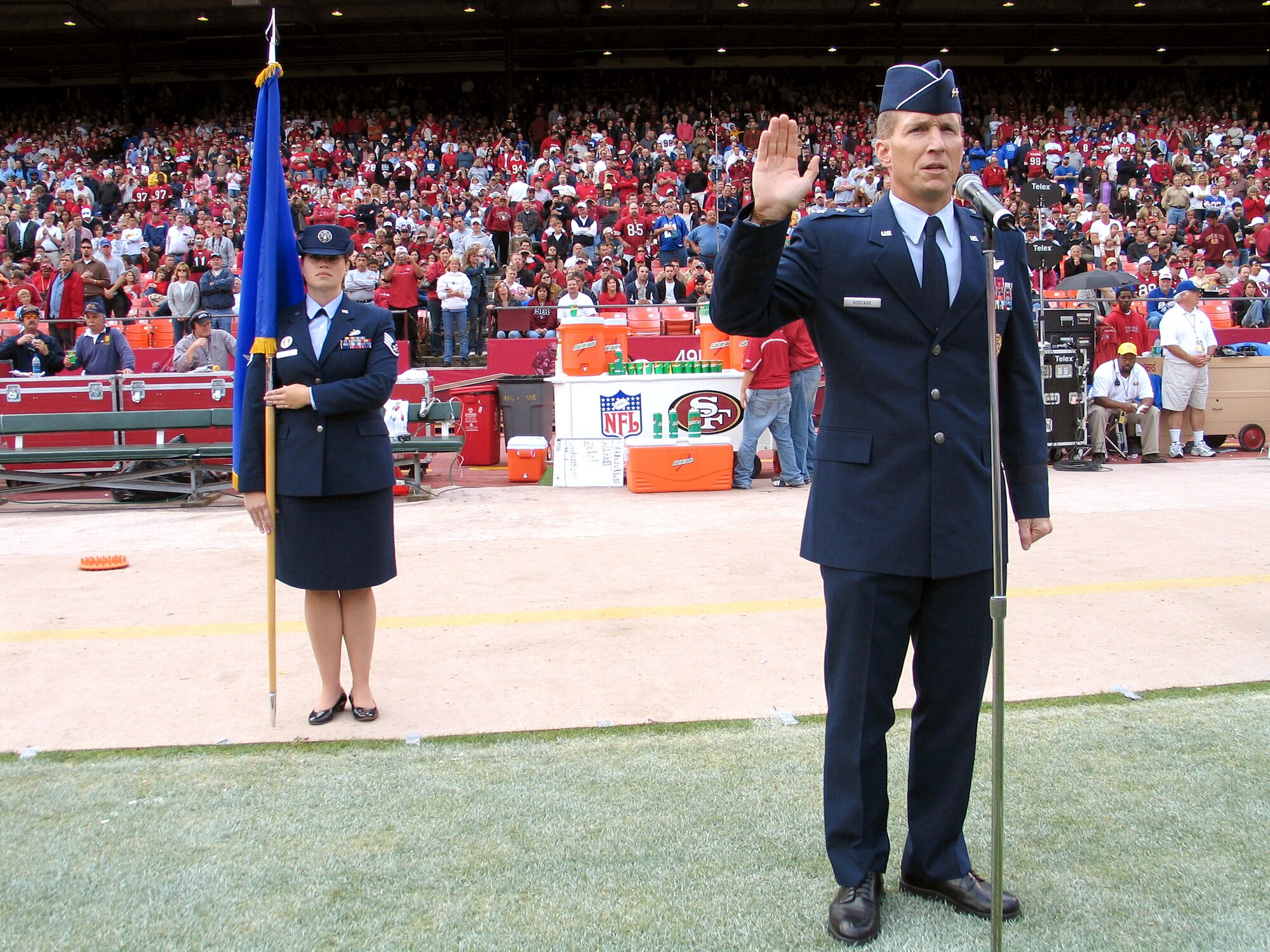 SAN FRANCISCO, Calif. (AFPN) -- Maj. Gen. Gilmary Michael Hostage III officiates an Air Force swear-in ceremony at a San Francisco 49ers halftime show here Nov. 6. Staff Sgt. Valerie Gordon, holds the two-star general flag behind him. The general is the director of operations at Air Education and Training Command, Randolph Air Force Base, Texas. Sergeant Gordon is with the 364th Recruiting Squadron recruiter. (U.S. Air Force photo by Staff Sgt. Connie Bias)