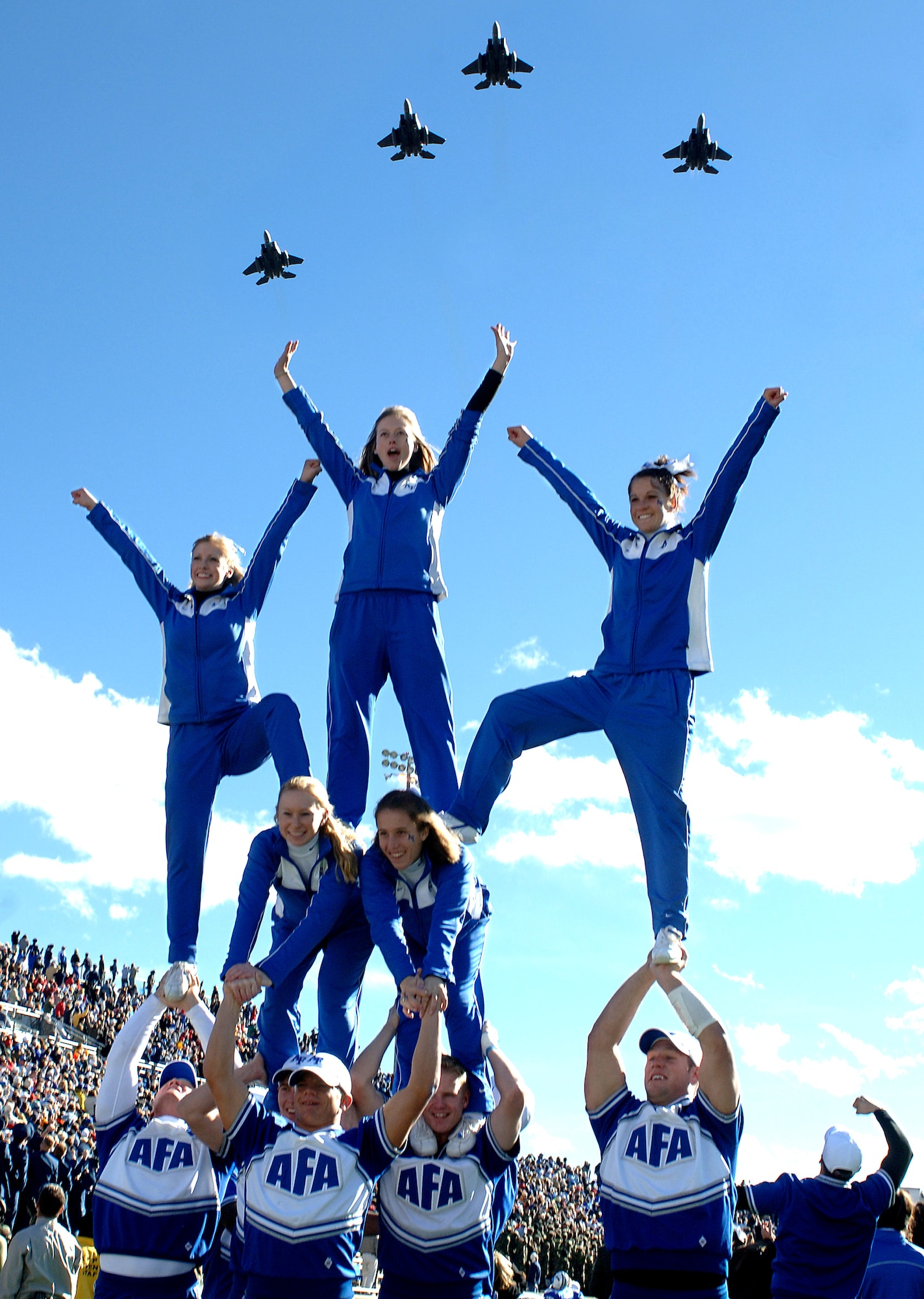 U.S. AIR FORCE ACADEMY, Colo. (AFPN) -- Air Force cheerleaders go through their paces prior to the opening kickoff against Army, as a quartet of F-15E Strike Eagles from the 90th Fighter Squadron, Elmendorf Air Force Base, Alaska, perform a fly over. (U.S. Air Force photo by Joel Strayer)