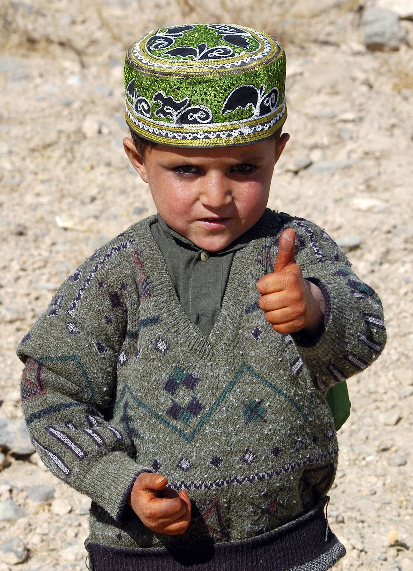 PARWAN PROVINCE, Afghanistan (AFPN) -- An Afghan boy gives a "thumbs up" following the distribution of supplies as part of an adopt-a-village visit here. Airmen participating in the ongoing global war on terrorism at nearby Bagram Air Base took time to spread some cheer and share smiles with the people of Afghanistan. The Airmen gave out more than 1,200 pounds of winter clothes, blankets, toys and school supplies. (U.S. Air Force photo by Staff Sgt. Marcus McDonald)