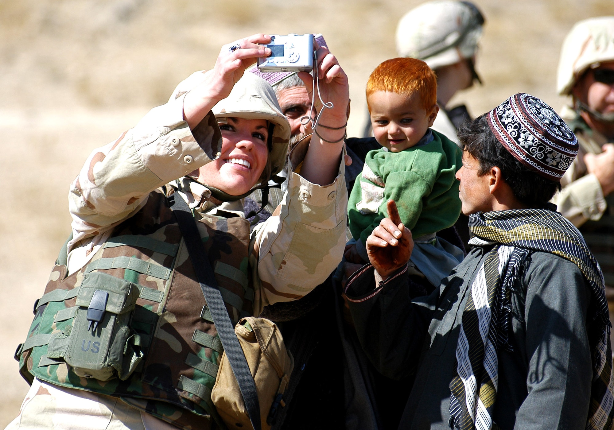 PARWAN PROVINCE, Afghanistan (AFPN) -- Senior Airman Tess Pottratz joins local villagers in a photo opportunity during an adopt-a-village visit here. Airman Pottratz and others took time to spread some cheer and share smiles with the people of Afghanistan as part of the humanitarian relief effort. More than 1,200 pounds of winter clothes, blankets, school supplies and toys were distributed to the local village. Airman Pottratz is deployed to Bagram Air Base from McChord Air Force Base, Wash. (U.S. Air Force photo by Staff Sgt. Marcus McDonald) 