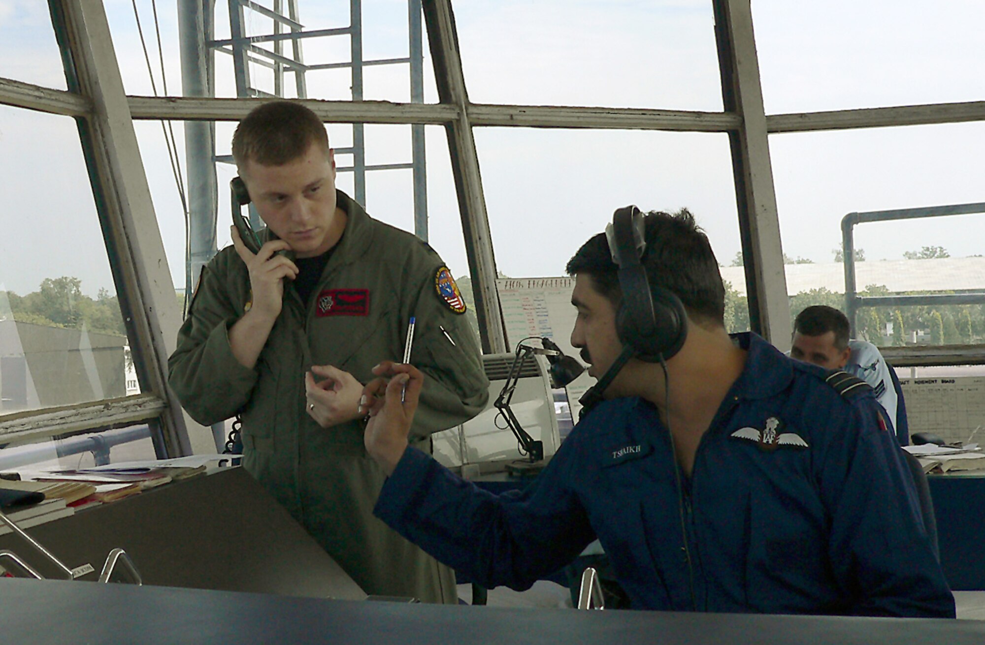 KALAIKUNDA AIR STATION, India (AFPN) -- Capt. Benjamin Freeborn and Indian Air Force Squadron Leader Tahir Shaikh discuss the order in which aircraft return to base following sorties during the Cope India exercise here. Captain Freeborn works in the air traffic control tower as the supervisor of flying for American Airmen. Squadron Leader Shaikh is the senior launch coordinator for Indian Airmen. Both deployed here for Cope India 06, which began Nov. 7. The exercise will enhance interoperability between the two air forces. (U.S. Air Force photo by Capt. John Redfield)