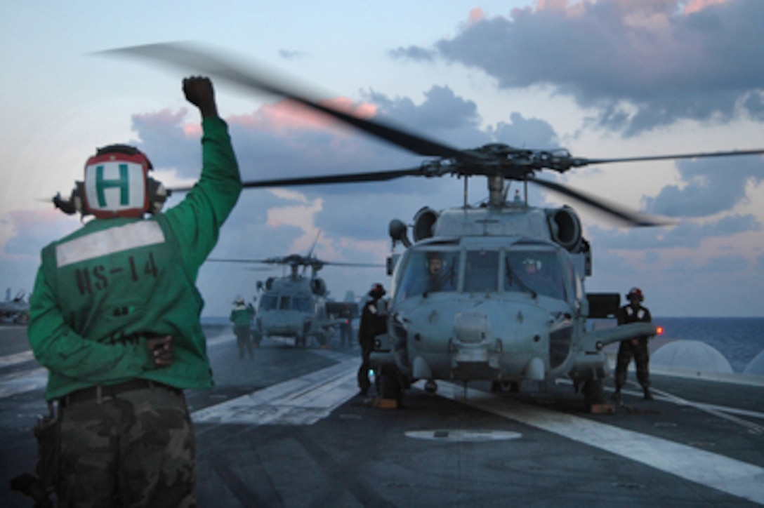 A flight deck crewman signals to the pilots of an HH-60H Seahawk helicopter to hold on the flight deck of the aircraft carrier USS Kitty Hawk (CV 63) on Nov. 2, 2005. The Kitty Hawk Carrier Strike Group is operating in the western Pacific Ocean from its homeport of Yokosuka, Japan. 