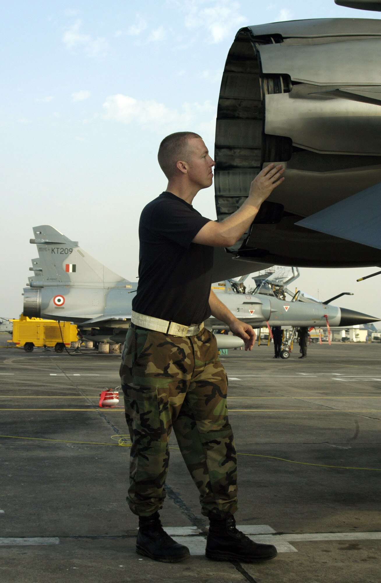 KALAIKUNDA AIR STATION, India -- Crew chief Staff Sgt. Garrett Faust inspects the exhaust nozzle on his the F-16 Fighting Falcon here. The Falcons are flying dissimilar air combat sorties against Indian Mirage fighters -- like in the background -- and other aircraft during exercise Cope India 06, which ends Nov. 19. The sergeant is from the 35th Aircraft Maintenance Squadron at Misawa Air Base, Japan. (U.S. Air Force photo by Tech. Sgt. Martin Jackson)

