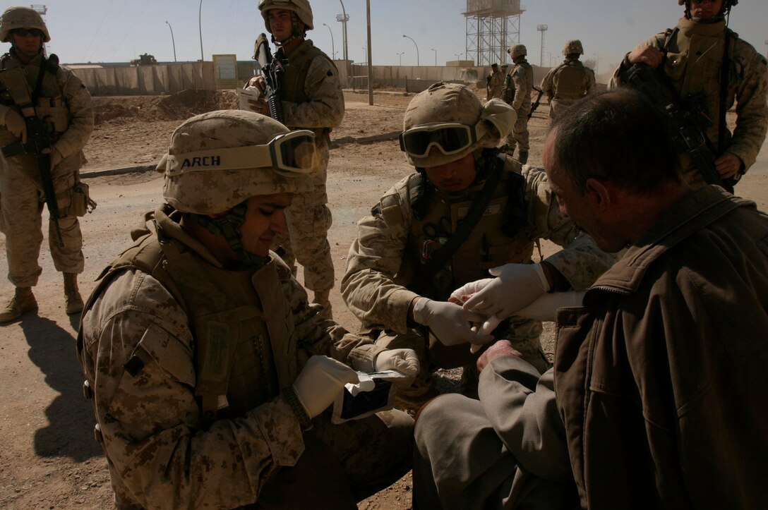 Seamen Manuel A. Arciniegas (left) and Lester E. Spence treat a resident of Husaybah, Iraq, outside of a forward operating base here. Both are corpsmen assigned to 8th Engineer Support Battalion, Combat Logistics Battalion-2, 2nd Marine Logistics Group (Forward).