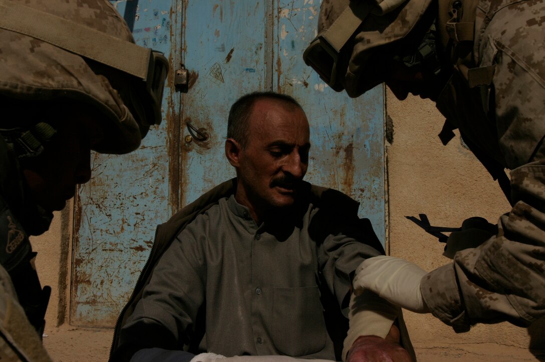 Seamen Manuel A. Arciniegas (right) and Lester E. Spence treat a resident of Husaybah, Iraq, outside of a forward operating base here. Both are corpsmen assigned to 8th Engineer Support Battalion, Combat Logistics Battalion-2, 2nd Marine Logistics Group (Forward).