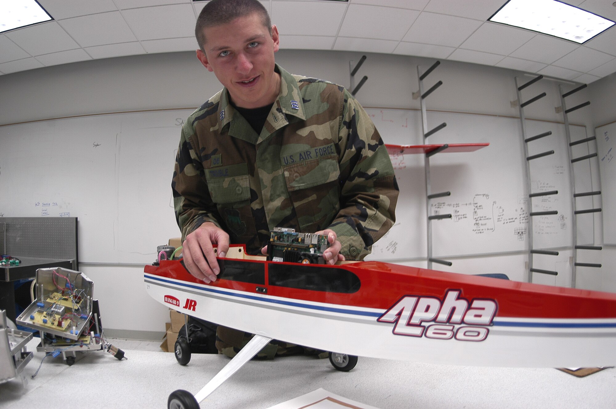 U.S. AIR FORCE ACADEMY, Colo. (AFPN) -- Cadet 1st Class James Trimble demonstrates how the network component he helped design will fit inside a UAV. An in-air network will allow multiple UAVs to communicate with each other as they accomplish tasks in groups.  (U.S. Air Force photo by Eddie Kovsky)