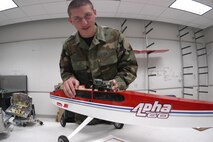 U.S. AIR FORCE ACADEMY, Colo. (AFPN) -- Cadet 1st Class James Trimble demonstrates how the network component he helped design will fit inside a UAV. An in-air network will allow multiple UAVs to communicate with each other as they accomplish tasks in groups.  (U.S. Air Force photo by Eddie Kovsky)