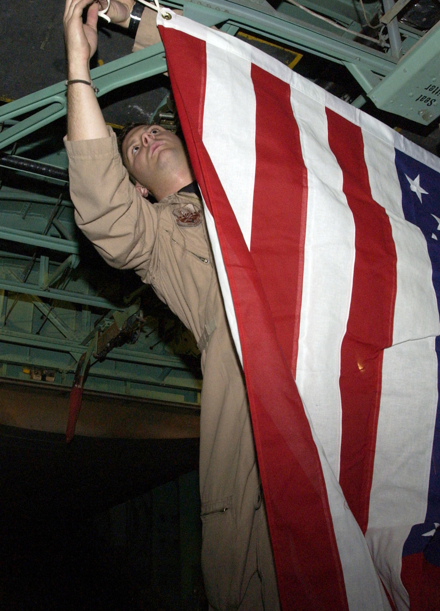 SOUTHWEST ASIA (AFPN) -- Senior Airman Greg Nardone hangs a flag in the cargo bay of a 1962 C-130E prior to take off. Airman Nardone is deployed here from Pope Air Force Base, N.C. He is a loadmaster with the 737th Expeditionary Airlift Squadron. (U.S. Air Force photo by Senior Airman Michael Garza) 

