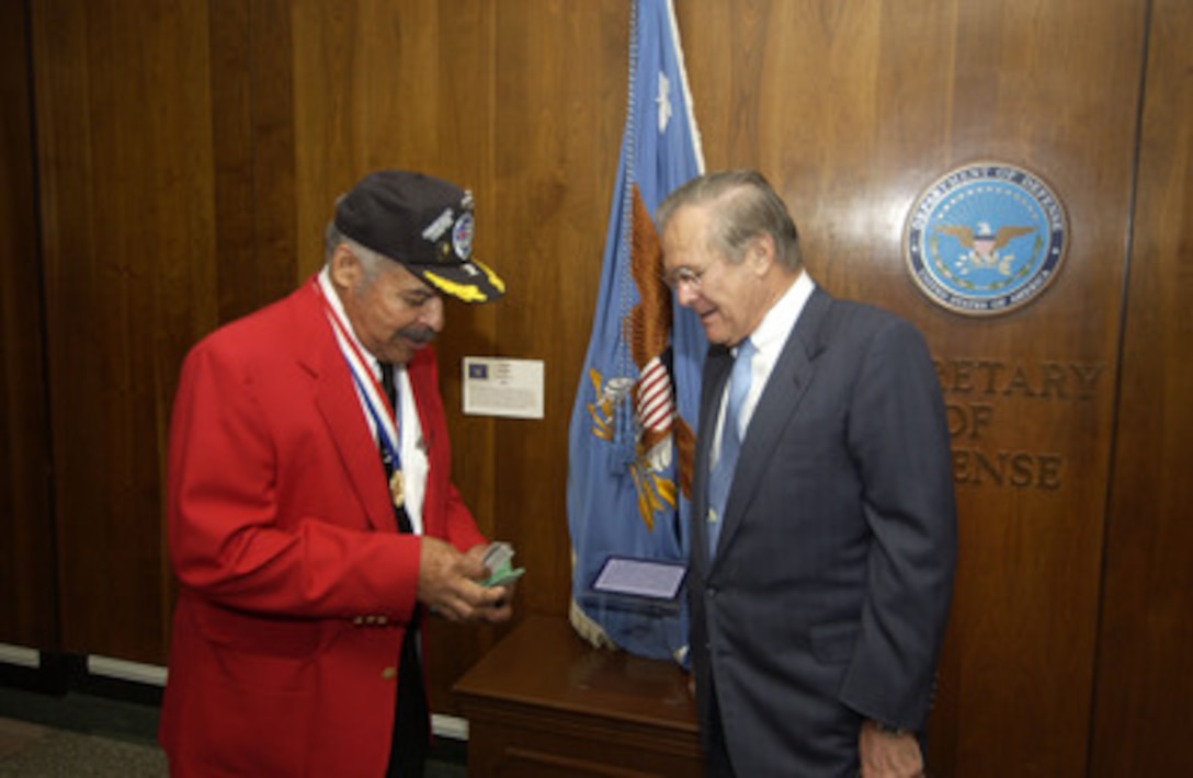 Tuskegee Airman retired Col. Porcher L. Taylor Jr. pulls out one of his business cards to give to Secretary of Defense Donald H. Rumsfeld in the Pentagon on Nov. 10, 2005. Taylor and some of his fellow airmen are at the Pentagon to receive briefings on the state of the Air Force, an update on global operations and have lunch with Rumsfeld. During World War II, the Tuskegee Airmen were credited with destroying 261 aircraft, damaging 148 aircraft, flying 15,553 combat sorties and 1,578 missions over Italy and North Africa. They destroyed or damaged over 950 units of ground transportation and escorted more than 200 bombing missions. As an escort fighter wing during World War II, they never lost a bomber to enemy fighters. 