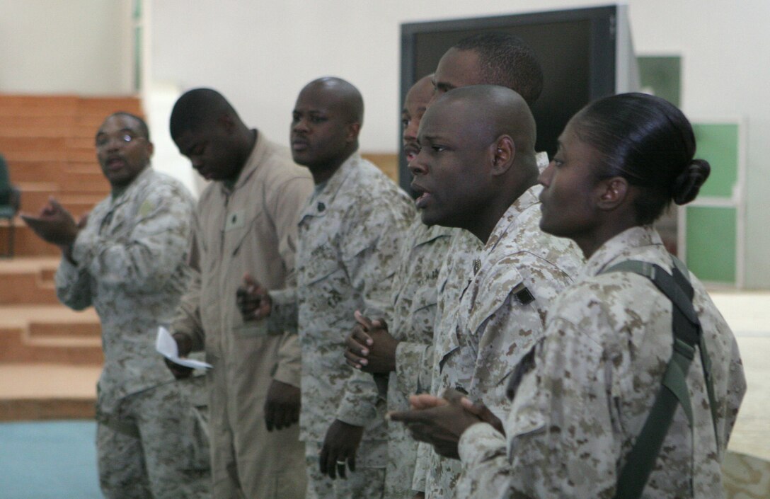 Gunnery Sgt. Terrance R. Moore, postal chief, Postal Detachment 6, Service Company, Headquarters and Service Battalion, 2nd Marine Logistics Group (FWD), and fellow service members here sing songs of inspiration during the gospel service Nov. 13, 2005. Moore has been instrumental in the religious programs throughout his multiple deployments.