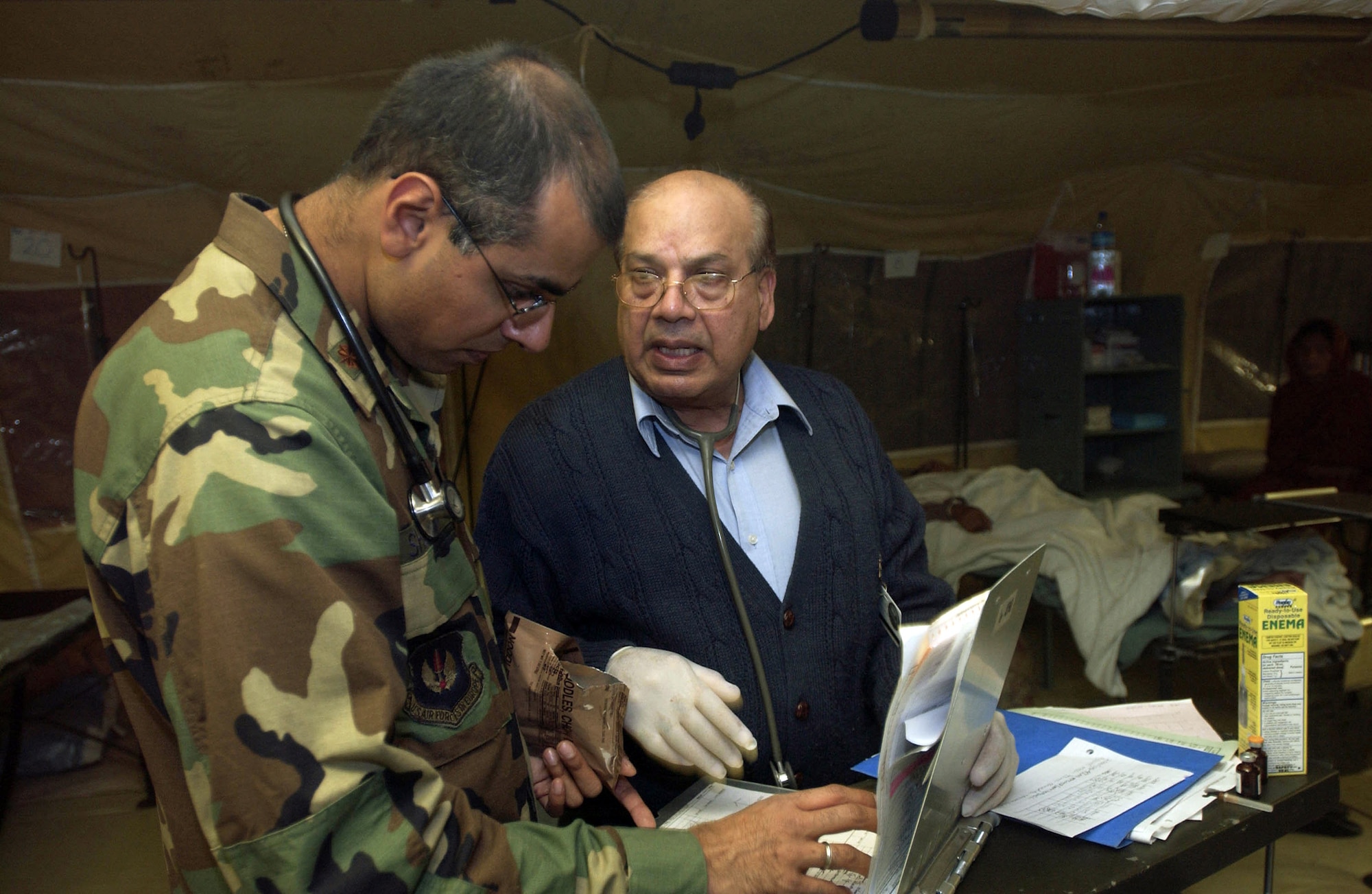 MUZAFFARABAD, Pakistan (AFPN) -- Maj. (Dr.) Fareed Sheikh (left) and his father Dr. Mushtaq Sheikh, a civilian physician, treat a patient at the 212th Mobile Army Surgical Hospital unit here.  Both doctors are Pakistani-Americans.  The hospital is helping with earthquake relief operations.  (U.S. Air Force photo by Staff Sgt. Quinton Russ)
