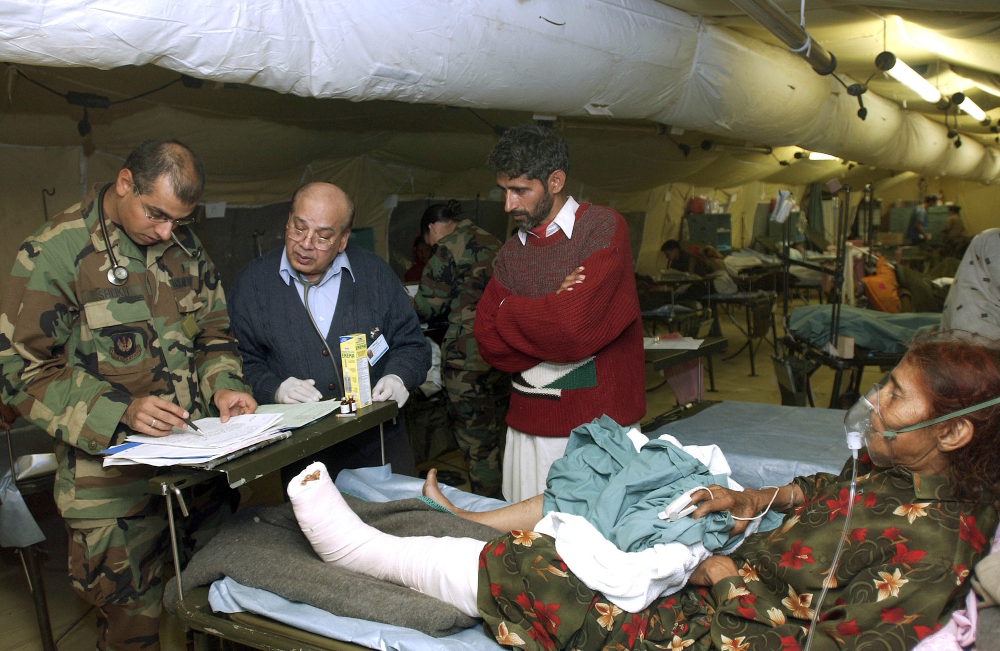 MUZAFFARABAD, Pakistan (AFPN) -- Maj. (Dr.) Fareed Sheikh (left) and his father, Dr. Mushtaq Sheikh, a civilian physician, treat a patient at the 212th Mobile Army Surgical Hospital unit here.  Both doctors are Pakistani-Americans.  The hospital is helping with earthquake relief operations.  (U.S. Air Force photo by Staff Sgt. Quinton Russ)
