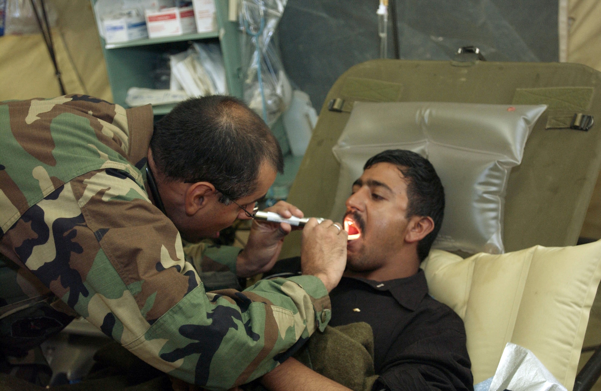 MUZAFFARABAD, Pakistan (AFPN) -- Maj. (Dr.) Fareed Sheikh checks a patient's tonsils at the 212th Mobile Army Surgical Hospital unit here.  Major Sheikh is assigned to the 212th MASH taking part in earthquake recovery operations in Pakistan.  (U.S. Air Force photo by Staff Sgt. Quinton Russ)