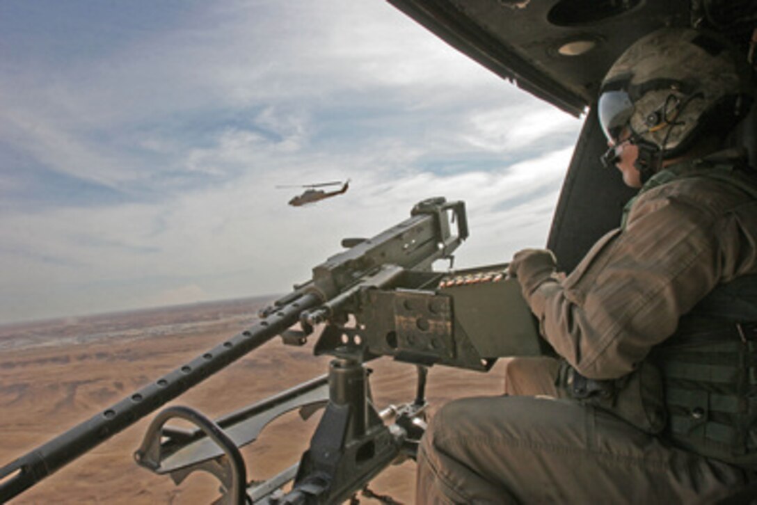U.S. Marine Corps Sgt. Jacy Alexander scans the desert below during an armed reconnaissance mission in the vicinity of Haditha, Iraq, on Nov. 3, 2005. Alexander is a UH-1N Huey helicopter crew chief assigned to Marine Light Attack Helicopter Squadron 167. 