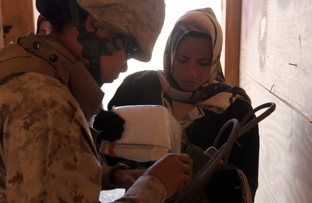Lance Cpl. Joyce N. Fundweburk searches through an Iraqi women?s purse here Nov. 16. Female Marines from various units within Combat Logistics Brigade-8, 2nd Marine Logistics Group, stand at the gates of Fallujah to ensure the city remains safe by checking female Iraqis for dangerous materials. Fundweburk is a supply warehouseman with CLB-8, 2nd MLG.