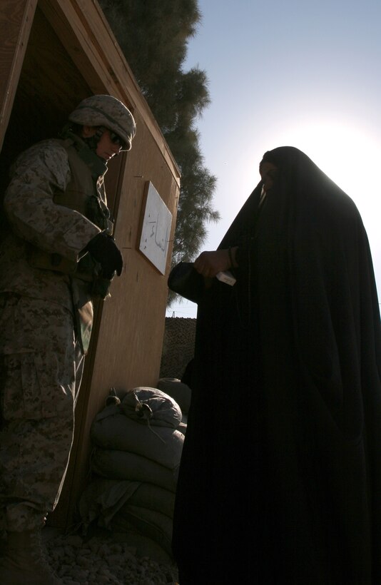 Lance Cpl. Riki M. Aguirre prepares to search female Iraqi here Nov. 16. Female Marines from various units within Combat Logistics Brigade-8, 2nd Marine Logistics Group, stand at the gates of Fallujah to ensure the city remains safe by checking female Iraqis for dangerous materials. Aguirre is a field radio operator with Headquarters and Service Company, CLB-8, 2nd MLG.
