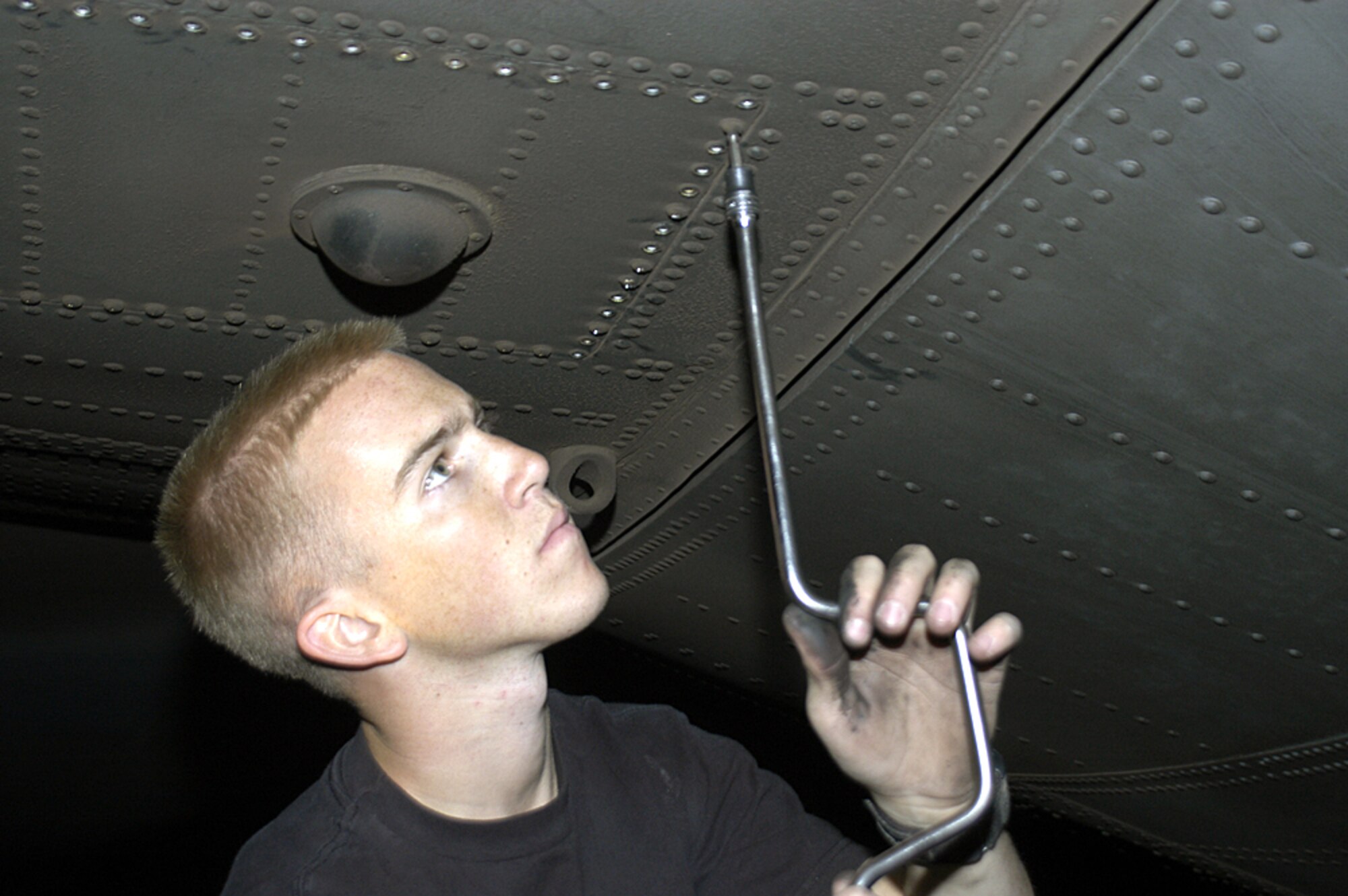 MOSUL, Iraq (AFPN) -- Senior Airman Brian Kundick removes the bolts from an access panel to reach the mounting bolts of a failed elevator booster pack on a C-130 Hercules stranded here. The pack lets the rear wings move vertically, allowing the aircraft to ascend or descend in flight. He and Hydraulics specialist Staff Sgt. David Harrelson came here Nov. 12 to help get the cargo plane back in the air. The maintainers are deployed to Iraq with the 43rd Aircraft Maintenance Squadron from Pope AFB, N.C. (U.S. Air Force photo by Staff Sgt. Scott Campbell)