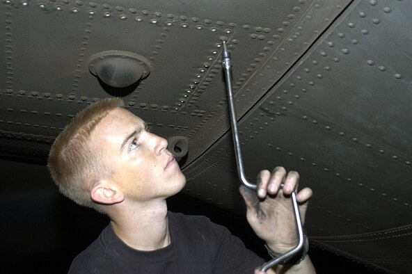 MOSUL, Iraq (AFPN) -- Senior Airman Brian Kundick removes the bolts from an access panel to reach the mounting bolts of a failed elevator booster pack on a C-130 Hercules stranded here. The pack lets the rear wings move vertically, allowing the aircraft to ascend or descend in flight. He and Hydraulics specialist Staff Sgt. David Harrelson came here Nov. 12 to help get the cargo plane back in the air. The maintainers are deployed to Iraq with the 43rd Aircraft Maintenance Squadron from Pope AFB, N.C. (U.S. Air Force photo by Staff Sgt. Scott Campbell)