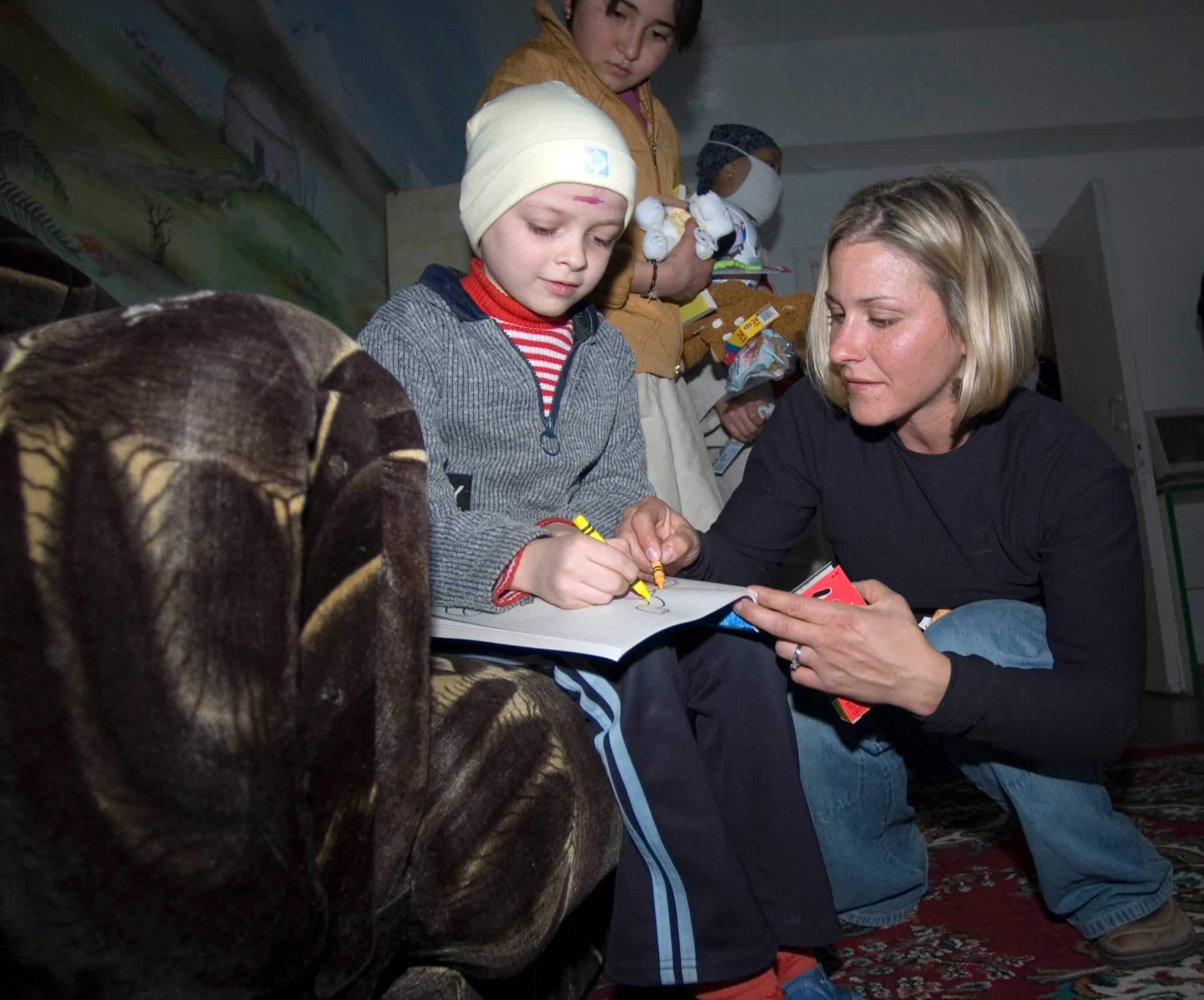 BISHKEK, Kyrgyzstan (AFPN) -- Staff Sgt. Ann Mitchell colors with Raya, a young Kyrgyz girl with cancer. He and other members of the Manas Air Base Outreach Society volunteer their day off to do the work at the center. Since 2003, the Airmen have donated more than $55,000 to help the needy of Kyrgyzstan. The sergeant is a 376th Expeditionary Services Squadron fitness instructor. (U.S. Air Force photo by Robin Hicks)