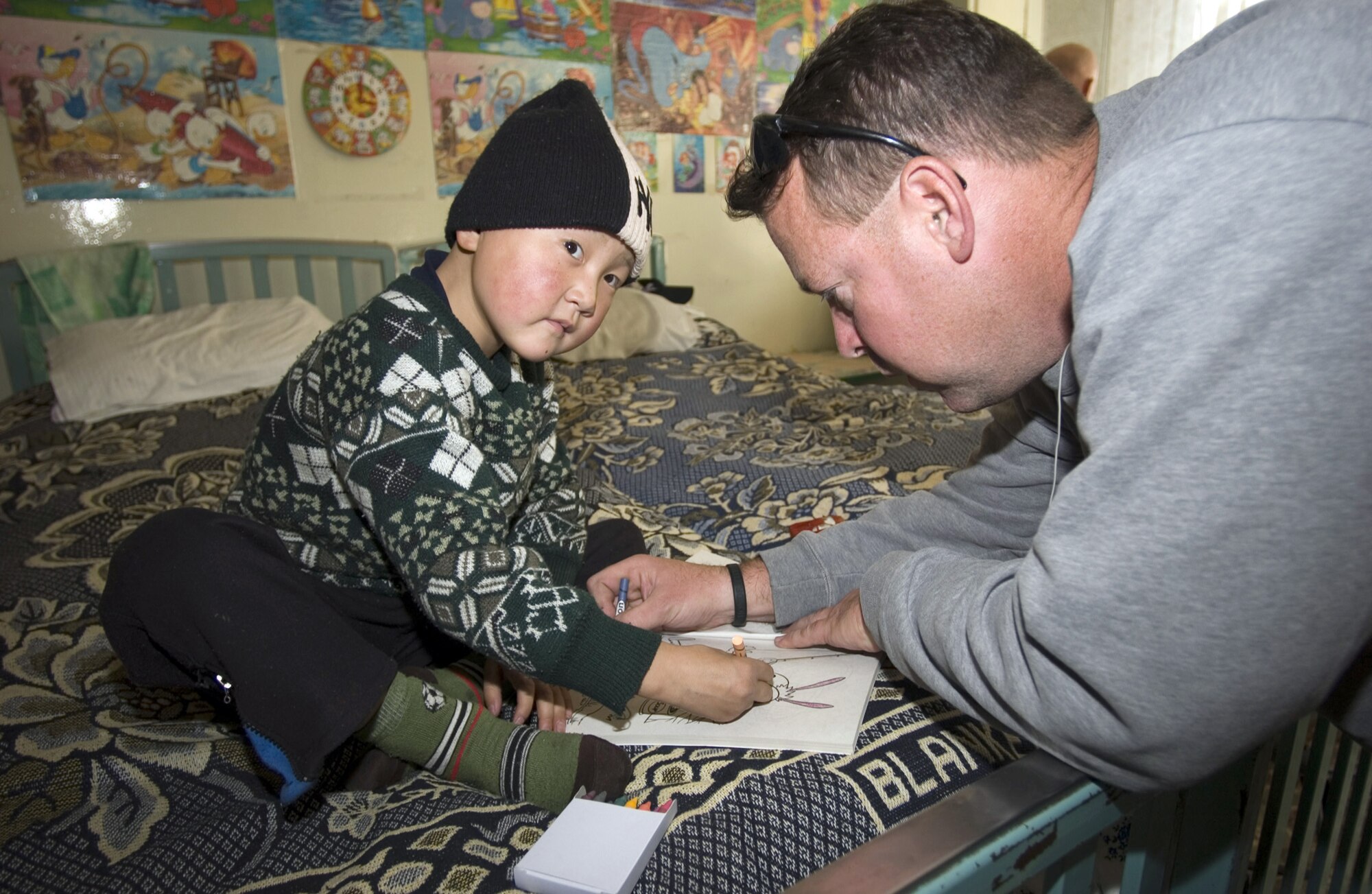 BISHKEK, Kyrgyzstan (AFPN) -- Master Sgt. Michael McKeithan colors with a young patient at the cancer center. As a member of the Manas Air Base Outreach Society the sergeant donates time and money to help improve the lives of needy Kyrgyz people. The sergeant is a member of the 376th Expeditionary Logistics Readiness Squadron. (U.S. Air Force photo by Robin Hicks)