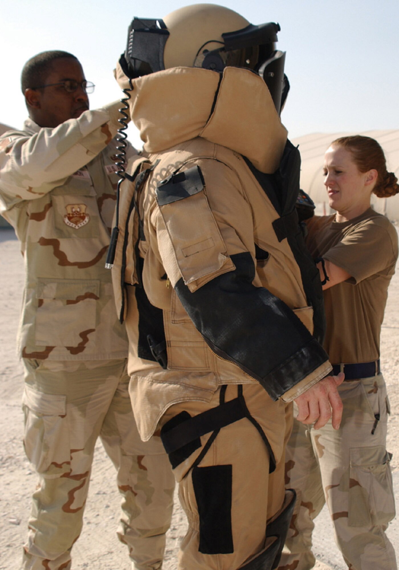 SOUTHWEST ASIA (AFPN) -- Tech. Sgt. Anthony Blackmon and Staff Sgt. Lindsey Leitz help Airman 1st Class Mark Kinney suit up for an explosive ordnance disposal training mission. The Airmen are with the 379th Expeditionary Civil Engineering Squadron explosive ordnance disposal unit at this base. (U.S. Air Force photo by Tech. Sgt. Sarah Webb)