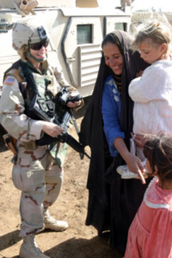 Army Lt. Col. Lynne Westlake talks with the mother of a little girl who just received a new pair of shoes in Haswa, Iraq, on Nov. 10, 2005. Westlake and her fellow soldiers of Bravo Company, 490th Civil Affairs Battalion, 155th Brigade Combat Team passed out donated shoes, toys and candy to the villagers near Haswa Firm Base. 