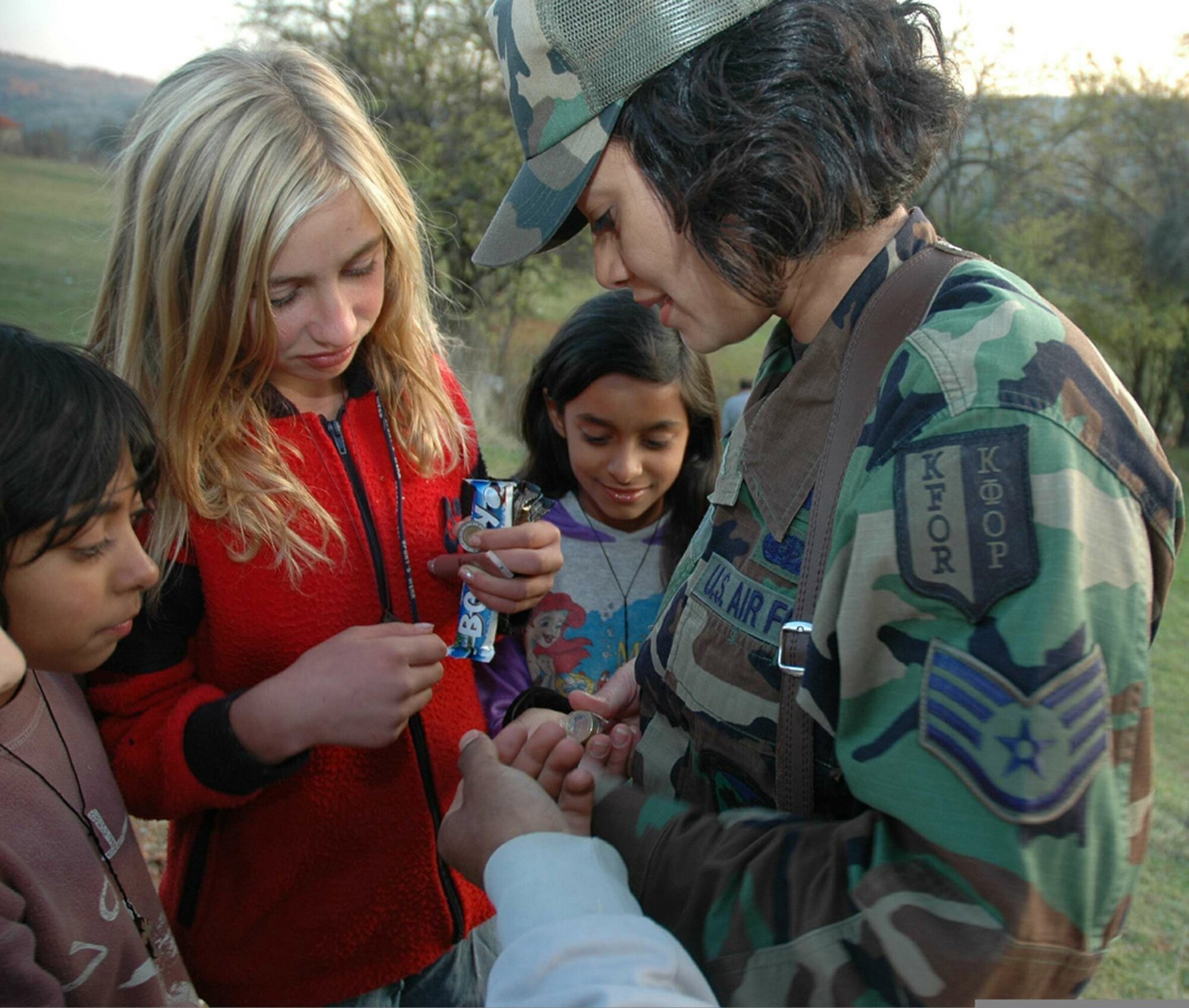 NOVO BRDO, Kosovo (AFPN) -- Children gather around Staff Sgt. Shannon Millard as she hands out coins and candy during a humanitarian mission in the Novo Brdo region of Kosovo. Shannon Millard is a contract specialist deployed from Cannon Air Force Base, N.M. (Ukranian Army photo by 1st Lt. Maksym Nedria)