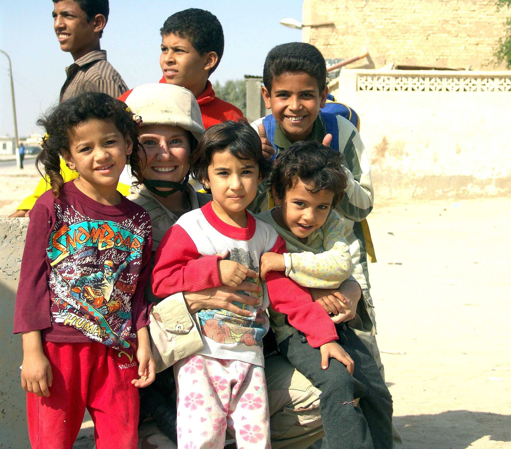UMM QASR, Iraq (AFPN) -- Senior Airman Jana Sautter poses with some Iraq children during a humanitarian relief mission in Umm Qasr, Iraq. Coalition forces delivered more than a thousand school supplies and toys to the children Nov. 14. Airman Sautter is assigned to the 568th Expeditionary Security Forces Squadron. (U.S. Air Force photo by Tech. Sgt. Mark Getsy) 

