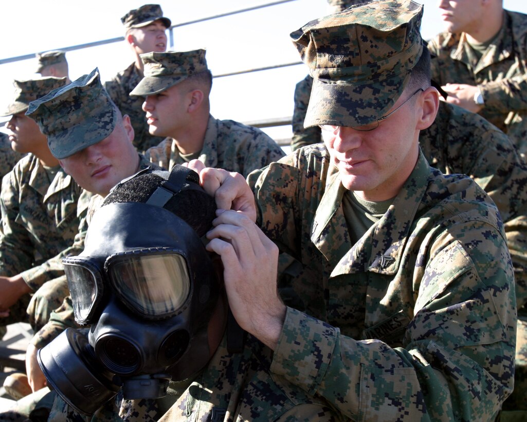 Cpl. James B. Weaver, right, helps Cpl. Derrick D. Shoto tighten his field protective mask during a mask confidence exercise at the 33 Area gas chamber here. Weaver and Shoto are both field radio operators with the 15th Marine Expeditionary Unit. The 15th MEU participated in the exercise to ensure that the individual Marines and Sailors in the unit are confident in their field protective mask while operating in a contaminated environment.