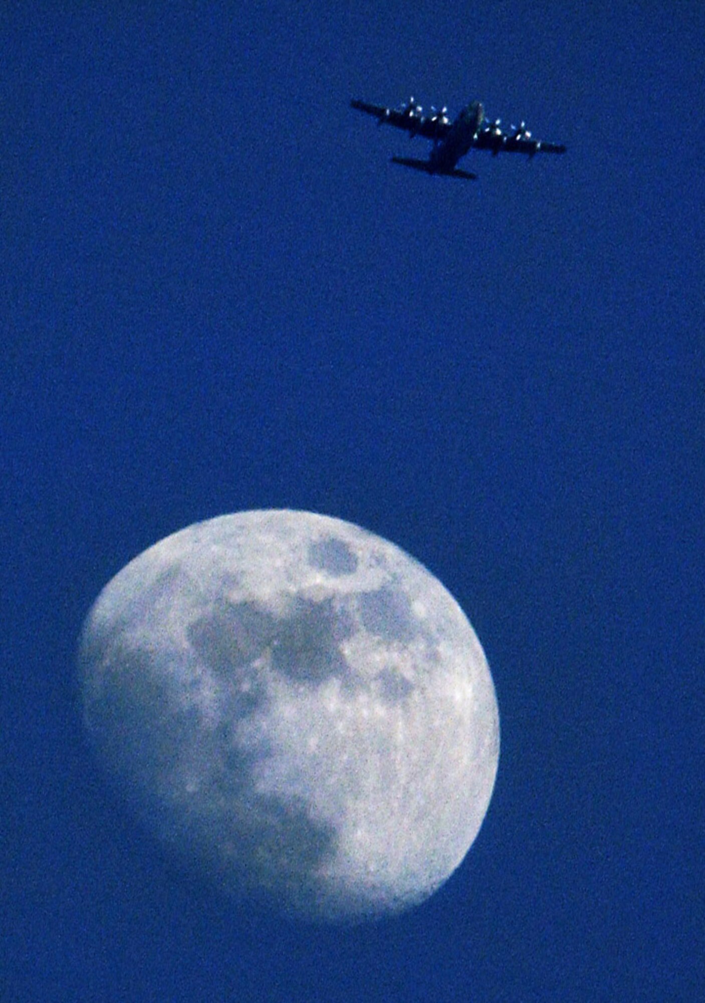 CAMP LEMONIER, Djibouti (AFPN) -- A C-130 Hercules of the 131st Rescue Squadron flies high over the Golf Drop Zone  -- and seemingly over the moon -- near this camp in the Horn of Africa. (U.S. Air Force photo by Staff Sgt. Stacy L. Pearsall)
