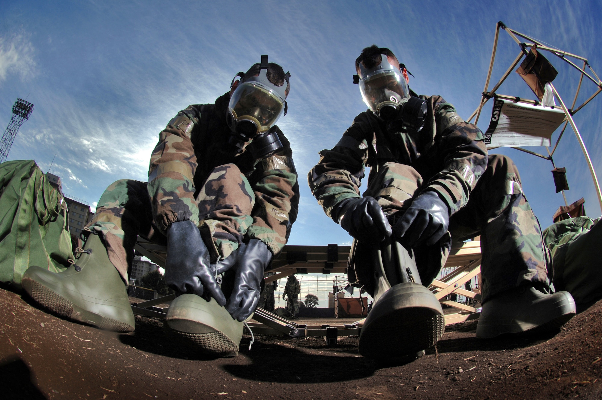 YOKOTA AIR BASE, Japan (AFPN) -- Staff Sgts. Mark Freeman (left) and Tom McCauley remove their protective overboots at the contaminated control area during "ability to survive and operate" training. Airmen with the 374th Arlift Wing refamiliarized themselves with protective procedures, planning post-reconnaissance attack routes and contaminated control area procedures during "readiness week." Both Airmen are aerospace ground equipment mechanics from the 374th Maintenance Squadron. (U.S. Air Force photo by Master Sgt. Val Gempis) 