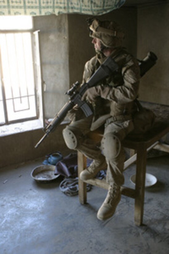 A U.S. Marine sits atop a table as he watches the street outside a window in Karabilah, Iraq, during Operation Steel Curtain on Nov. 11, 2005. The intent of Steel Curtain is to restore Iraqi sovereign control along the Iraq-Syria border and destroy the al Qaeda network operating throughout the Qaim region. 