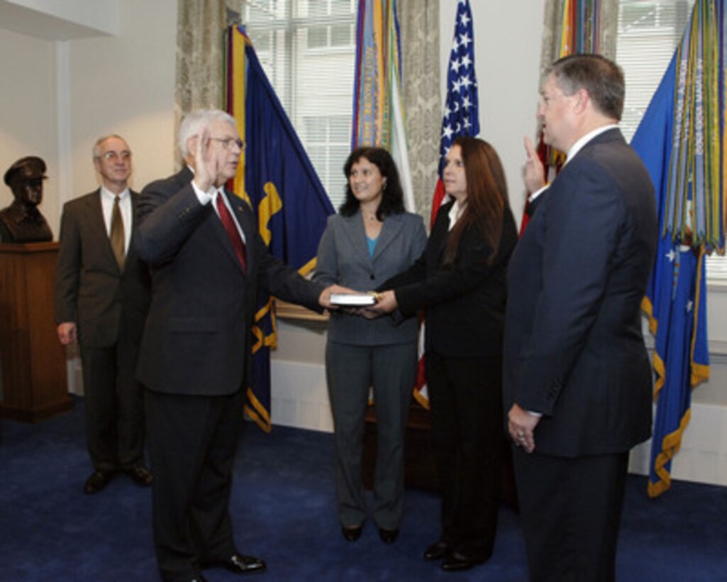 John G. Grimes (2nd from left) takes the oath of office as the Assistant Secretary of Defense for Networks and Information Integration and Department of Defense Chief Information Officer in a Pentagon ceremony on Nov. 14, 2005. Grimes' two daughters, Tammy Schubel and Terree Long, hold the Bible for their father as Director of Administration and Management Michael B. Donley (right) administers the oath. Acting Deputy Secretary of Defense Gordon England (left) watches as Grimes assumes the office. 
