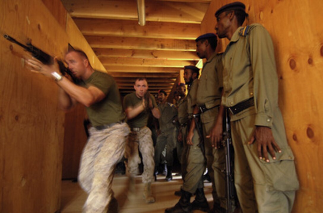 U.S. Marine Cpl. Steven Jacobs (left) and Sgt. Earnest Robke (center) show the Djiboutian Police how to move in teams of two through a hallway intersection during training at Camp Lemonier, Djibouti, on Nov. 16, 2005. U.S. Marine Central Command's 3rd Provisional Security Company is training members of the Direction General De La Police Nationale how to perform close quarters combat operations. 