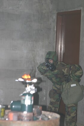CS capsules burn as a Marine stands in the gas chamber, performing the necessary actions for qualification.