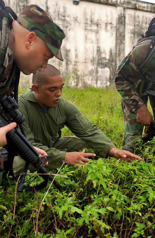 ANDERSEN AIR FORCE BASE, Guam -- Gilbert Augon instructs Staff Sgt. Darrell Simpson on what to look for when tracking a fugitive through lush vegetation Nov. 15. The Airmen with the 613th Contingency Response Group are learning tactical tracking techniques from the Guam Police Department during a weeklong course through the jungles of Guam. Mr. Quitugna is a Guam Police Tactical Tracker experienced in the unique methods that Sergeant Simpson will need in the on-base jungle.  (U.S. Air Force photo by Staff Sgt. Bennie J. Davis III) 