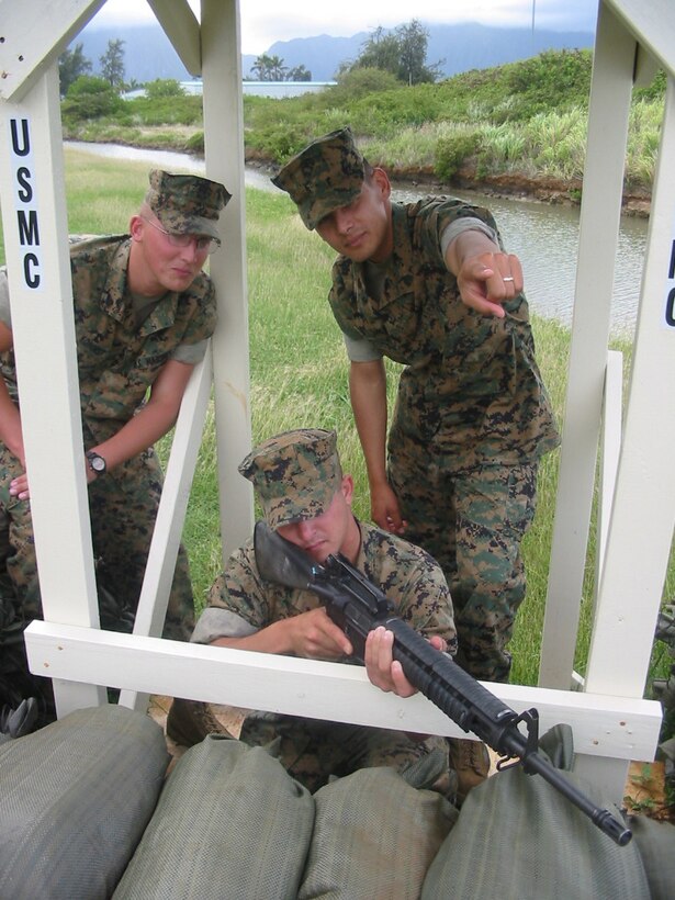 Sgt. Florencio Bermudez, squad leader, 3rd Platoon, Bravo Company, 1st Battalion, 3rd Marine Regiment, and a native of El Paso, Texas, points out possible fields of fire and avenues of approach to two rifleman from his squad  Lance Cpl. Bradley Kohorst (standing), from Geneva, Del., and Pfc. Matthew Terry (with rifle) from Katy, Texas  during sustainment training aboard Marine Corps Base Hawaii, Kaneohe Bay.