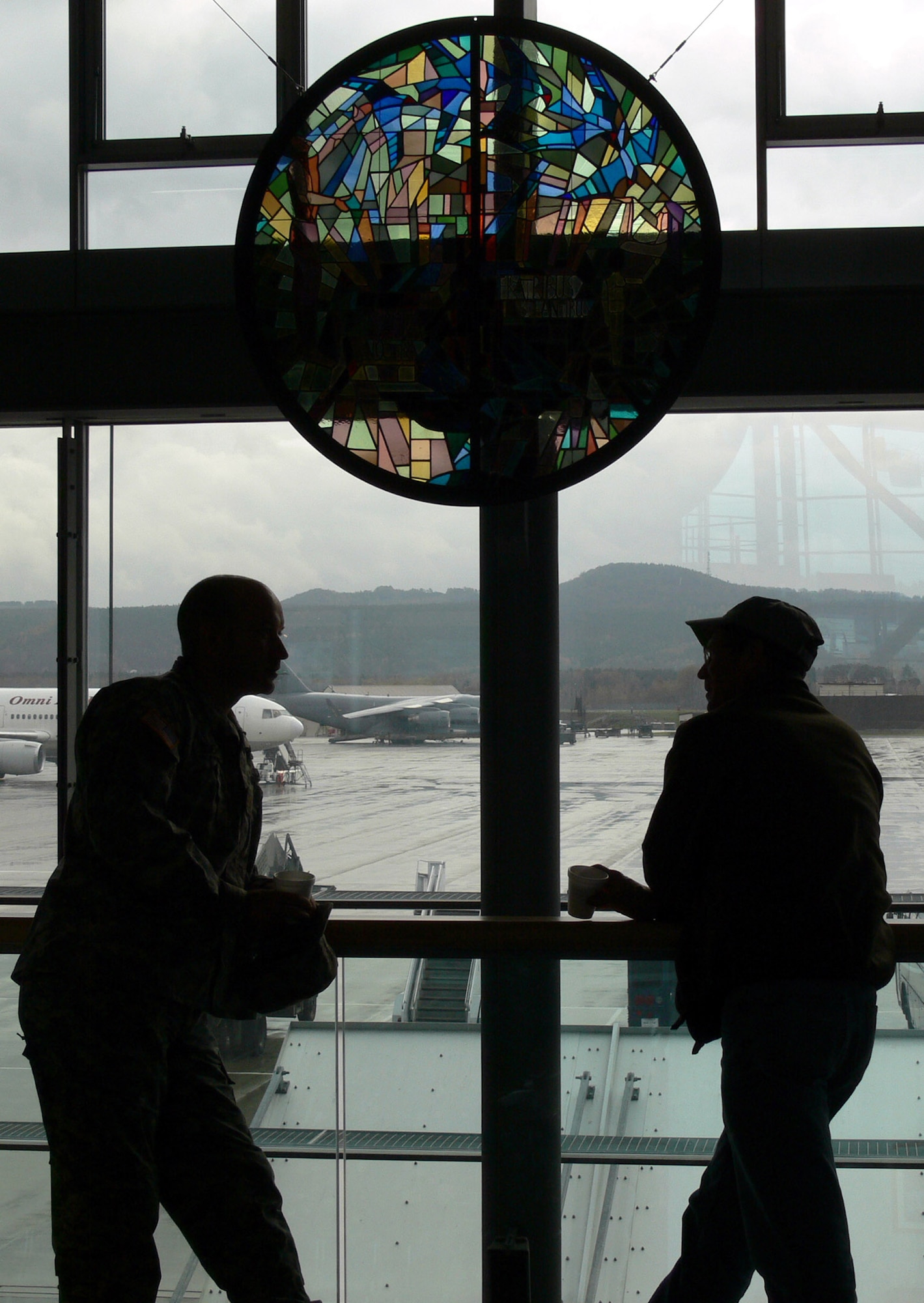 RAMSTEIN AIR BASE, Germany (AFPN) -- Two Airmen talk in front of a historic stained glass window at the Ramstein passenger terminal. The window was moved from Rhein-Main Air Base's chapel due to the base closing. (U.S. Air Force photo by Senior Airman Melissa Maraj)