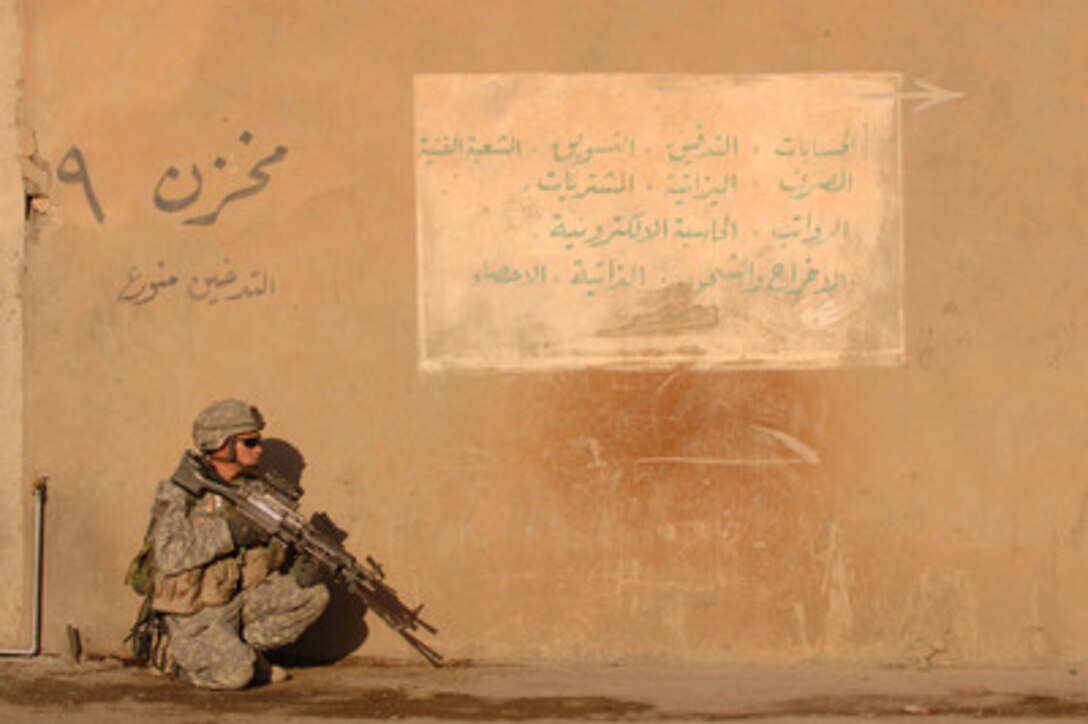 Army Spc. Kyle Shelton kneels next to a wall as he provides security for his fellow soldiers during a search in Mosul, Iraq, on Nov. 10, 2005. Shelton is attached to Charlie Company, 4th Battalion, 23rd Infantry Regiment, 172nd Stryker Brigade Combat Team. 
