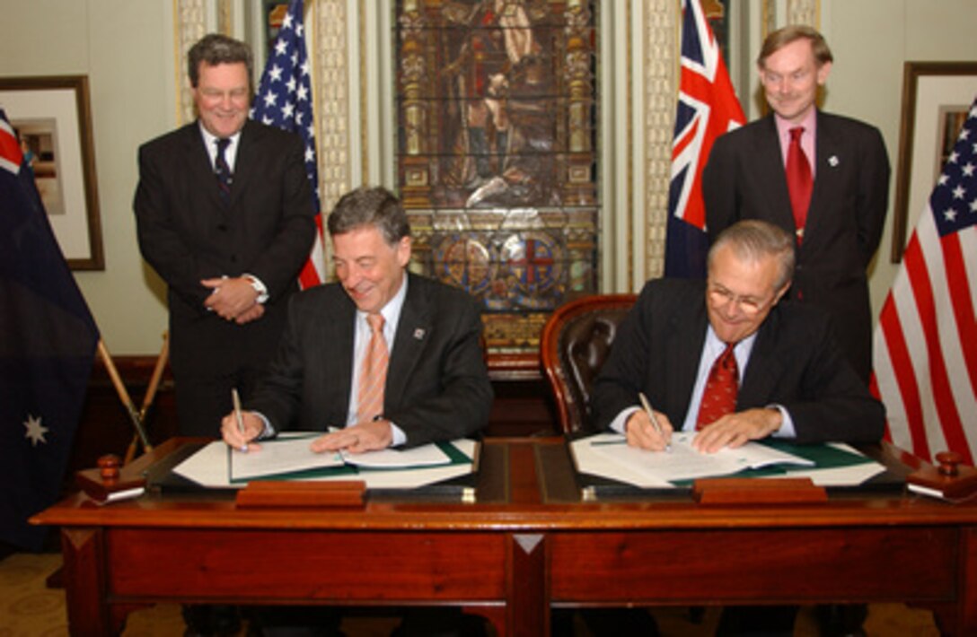 Secretary of Defense Donald H. Rumsfeld (right) and Australian Minister for Defense Robert Hill (left) sign a Memorandum of Understanding on joint combined training as U.S. Deputy Secretary of State Robert Zoellick (standing, right) and Australian Foreign Minister Alexander Downer look on at the Town Hall in Adelaide, Australia, on Nov. 18, 2005. Rumsfeld and Hill signed the memorandum at the conclusion of the annual Australian-United States Ministerial Conference. 