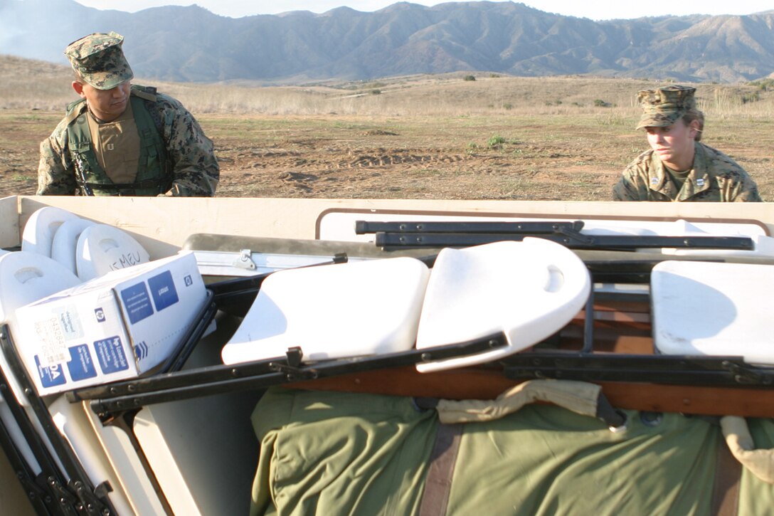Capt. Jose E. Almazan, adjutant, and Capt. Lisa M. Parrott, supply officer, both with the 15th Marine Expeditionary Unit, unloads chairs and tables used in Deployable Rapid Assembly Shelter tents. The 15th MEU conducted a Command Operation Center Exercise within the 25 Area here.