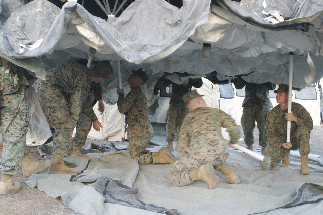 Marines from the 15th Marine Expeditionary Unit begin lifting the center of a  Deployable Rapid Assembly Shelter tent during the unit's Combat Operation Center Exercise in 25 Area here.
