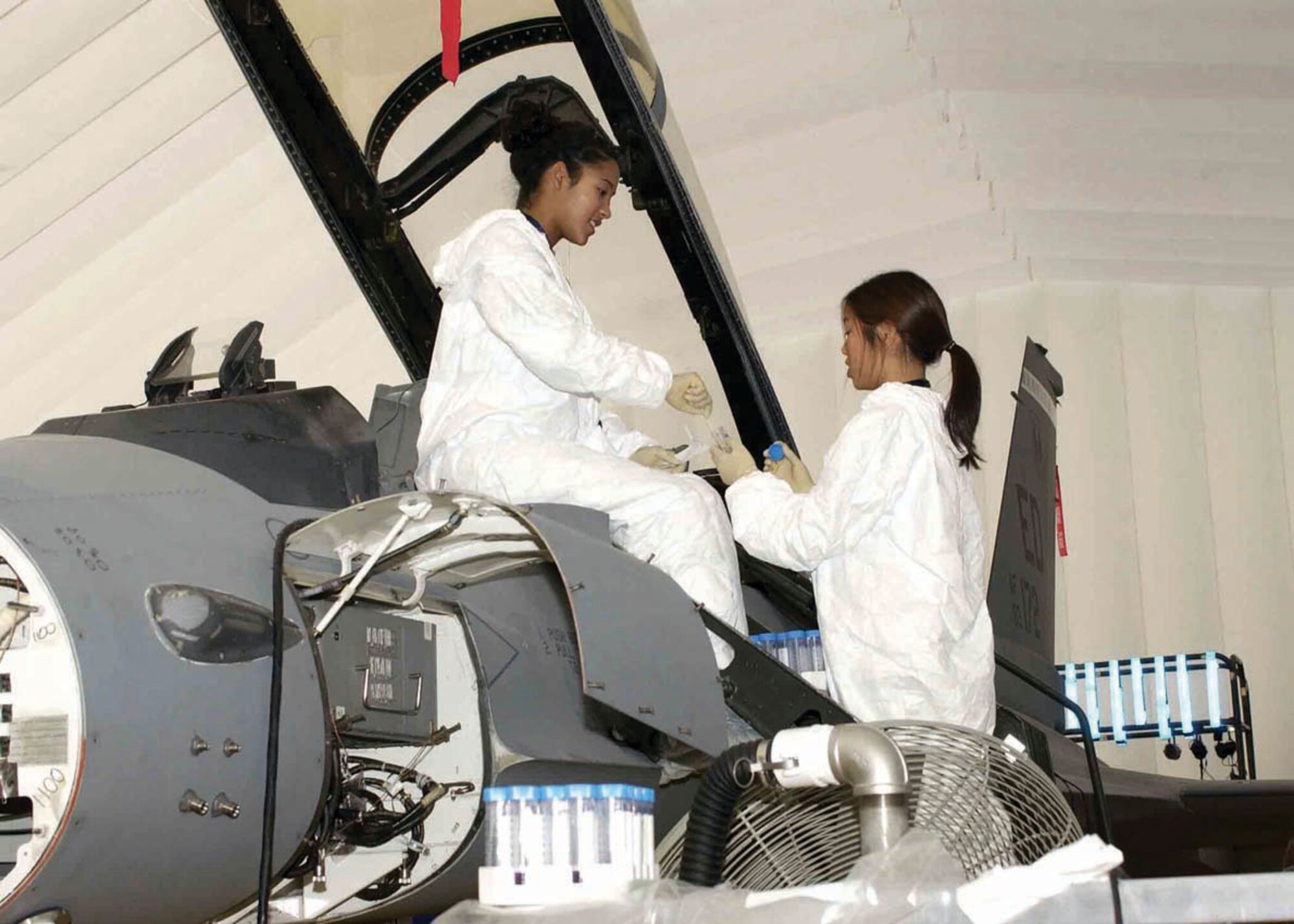 EDWARDS AIR FORCE BASE, Calif. (AFPN) -- Tina Slade and Jennifer Tanyatanaboon, prepare an F-16 Fighting Falcon for a biological contamination trial.  They are microbiologists with Battelle, the lead contractor for the Joint Strike Force decontamination project. (U.S. Air Force photo by Jeffrey Youngblood) 
