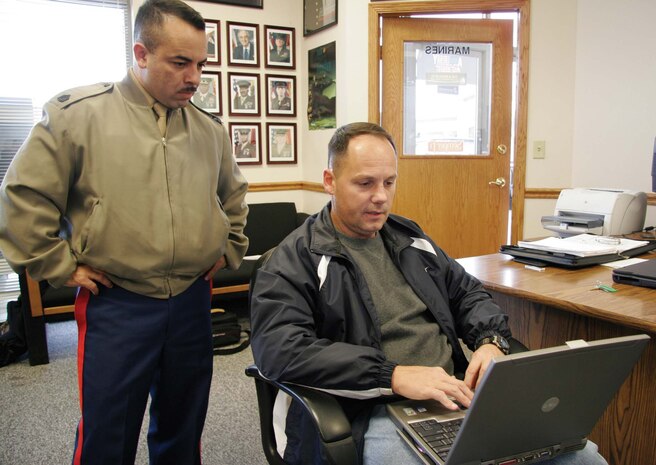 Recruiter Gunnery Sgt. Ciriaco R. Ayala, left, looks on as Rick Reitz, computer specialist, attempts to connect to a wireless network from within Recruiting Substation Des Moines, Iowa, on Nov. 23, 2005. Expanding their limited Web access in the Midwest, all 9th Marine Corps District recruiters are scheduled to soon be able to connect to the Internet using improved laptops and high-speed wireless modems. (Photo by Staff Sgt. Bill Lisbon)