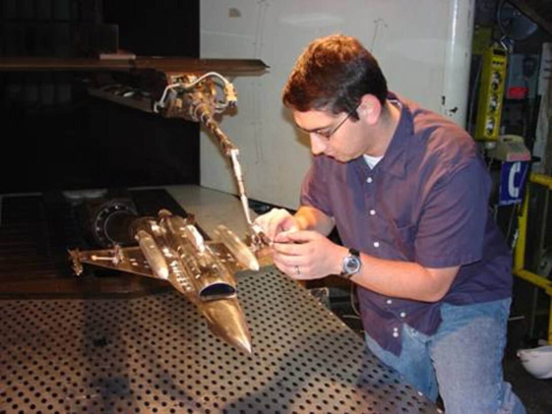 ARNOLD AIR FORCE BASE, Tenn. (AFMCNS) -- Adam Plondke, store separation project engineer, inspects the installation of the 1/20-scale model of the Miniature Air-Launched Decoy and F-16. Wind tunnel testing, which investigated the carriage and separation characteristics of the MALD from the F-16 at speeds up to Mach 0.95, was recently completed in the 4T wind tunnel. Use of the low-cost, air-launched, programmable decoys, which can accurately replicate the combat flight profiles and signatures of U.S. and coalition aircraft, is designed to deceive and confuse adversary air defense systems. (Air Force photo by Doyle Veazey)