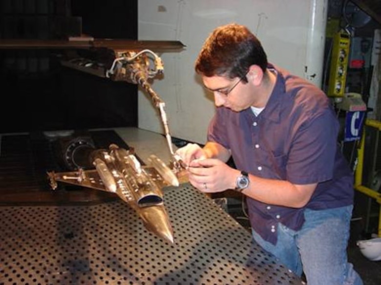 ARNOLD AIR FORCE BASE, Tenn. (AFMCNS) -- Adam Plondke, store separation project engineer, inspects the installation of the 1/20-scale model of the Miniature Air-Launched Decoy and F-16. Wind tunnel testing, which investigated the carriage and separation characteristics of the MALD from the F-16 at speeds up to Mach 0.95, was recently completed in the 4T wind tunnel. Use of the low-cost, air-launched, programmable decoys, which can accurately replicate the combat flight profiles and signatures of U.S. and coalition aircraft, is designed to deceive and confuse adversary air defense systems. (Air Force photo by Doyle Veazey)